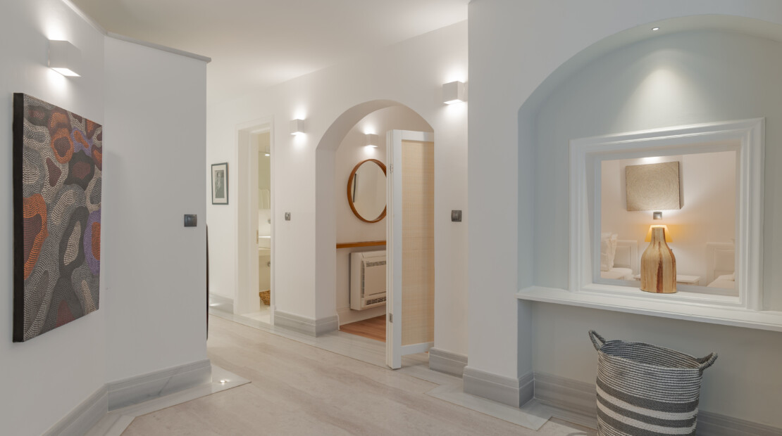 The bright corridor of our two bedroom luxurious apartments in Spetses with modern art on the wall and a glimpse of the twin beds