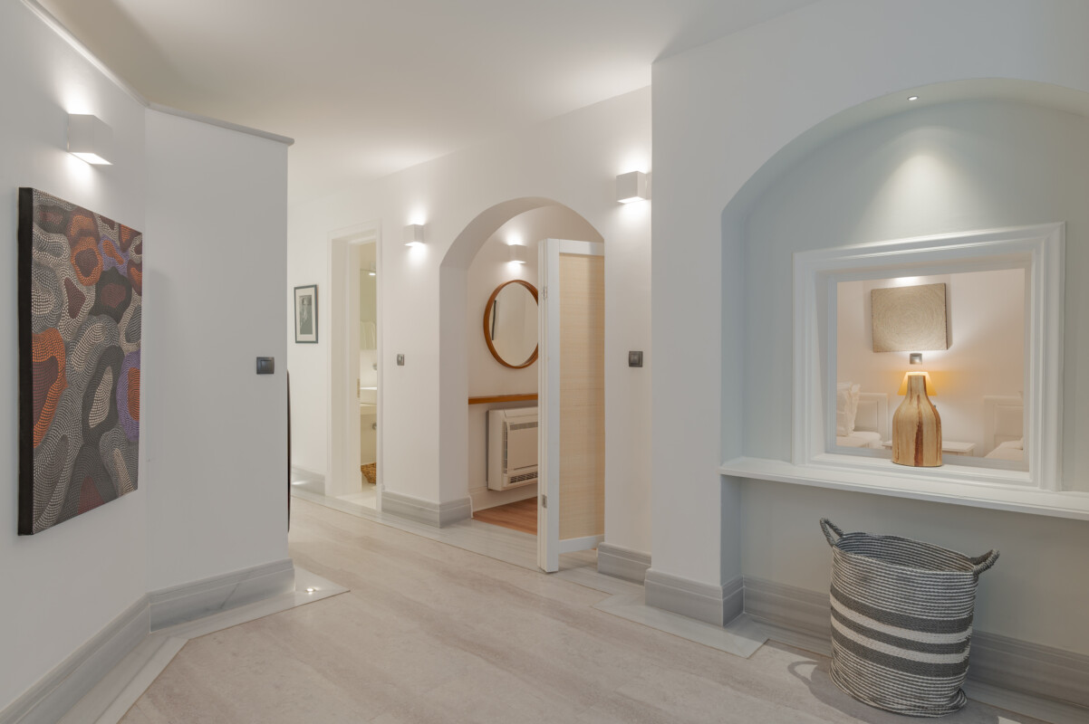 The bright corridor of our two bedroom luxurious apartments in Spetses with modern art on the wall and a glimpse of the twin beds