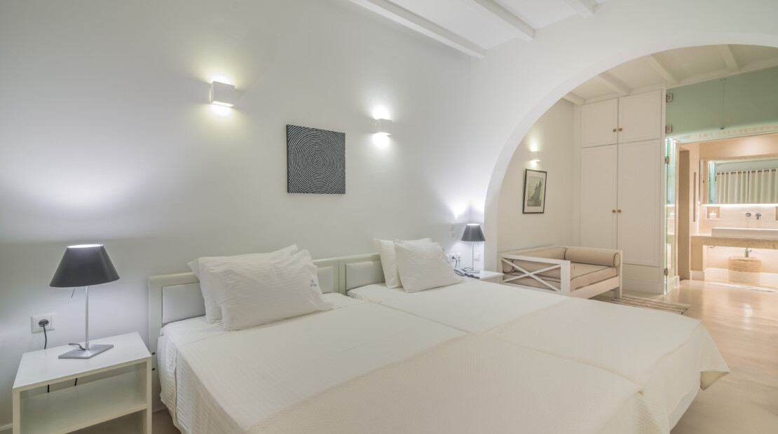 The bed and open space leading into the bathroom at Zoe's Club Double Sea view Room with balcony, Spetses island